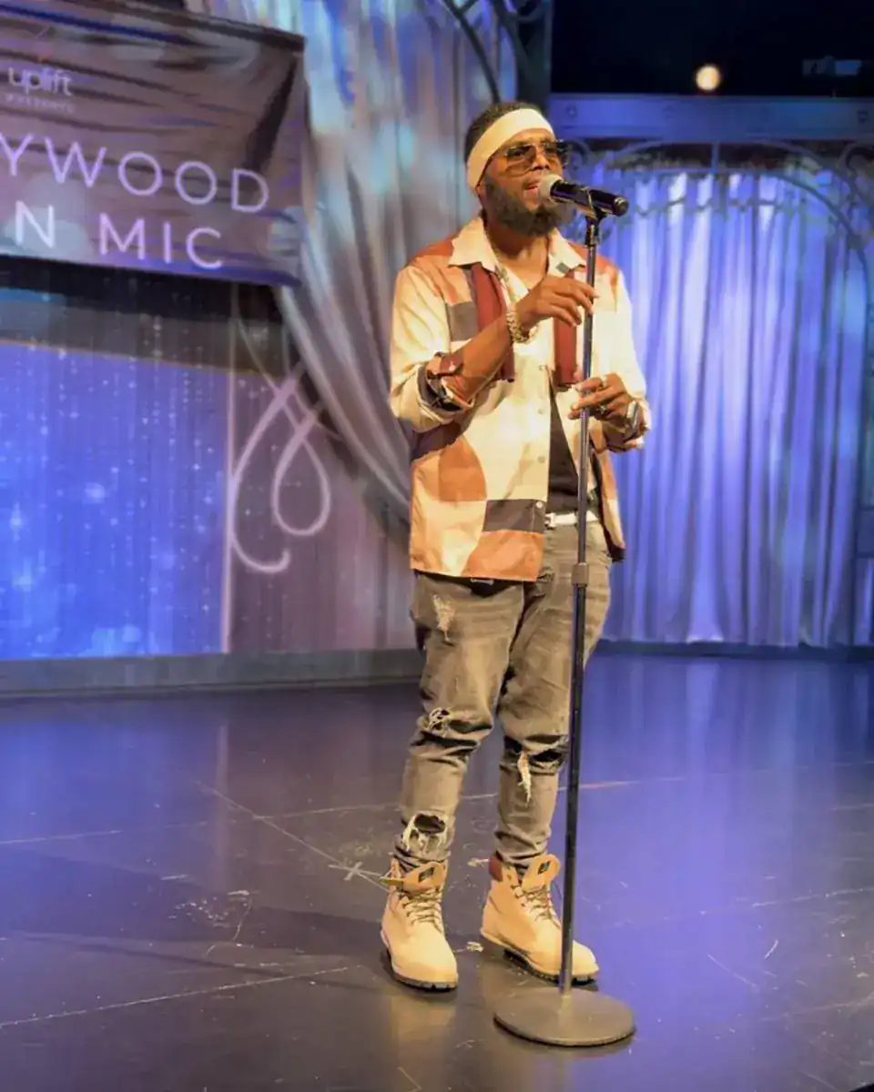 KingJu1c3 performing at a microphone on stage under blue light